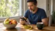 Como calcular TMB: homem com calculadora, fita métrica e tigela de frutas na mesa de casa